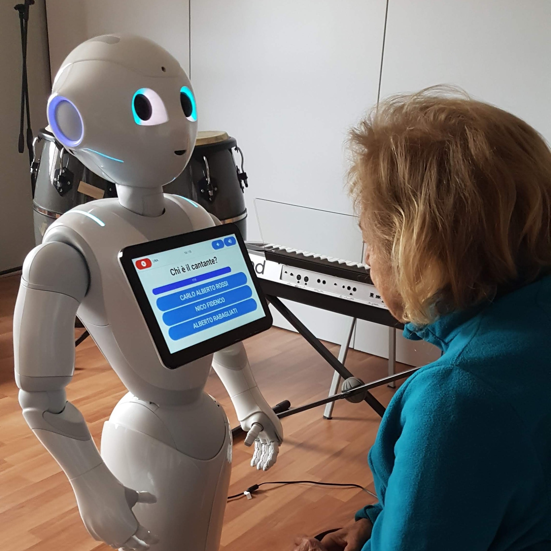 The image shows an old woman playing with Pepper, a humanoid robot